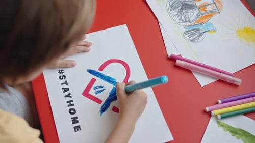 Child Drawing Stay Home Sign at Table