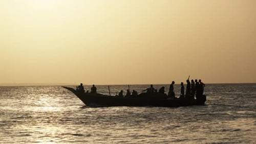 Silhouette d'un bateau de pêche africain avec un pêcheur naviguant dans l'océan au coucher du soleil