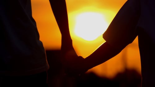 Couple Holding Hands at Golden Sunset