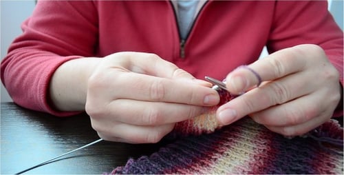 Hands Knitting Multi-Colored Patterned Material With Needles