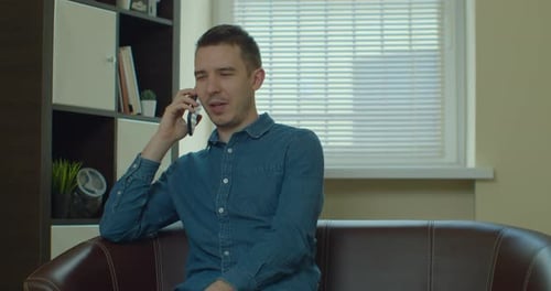 Man Talking on Phone While Sitting on Couch