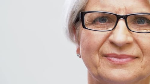 Senior Woman Adjusts Glasses in Close Up Shot
