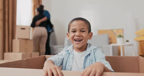 A Cute Little Boy Smiling Sits in a Cardboard Box Used for Packing Things During a Move the Child