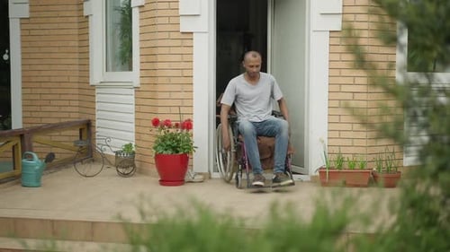 Paralyzed African American Man Riding Wheelchair on Backyard Porch Outdoors