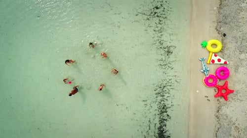 Aerial view of family playing volleyball in sea by sandy beach.