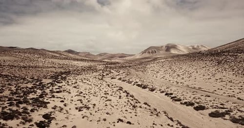 Path road in the middle of a mountains sand desert with blue bright sky in background. Arid climate