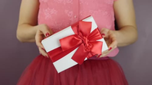 Woman Holding Out Decorative Present with Red Ribbon