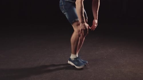 Un jeune mec pompé en short en jean faisant des exercices d'endurance pour son corps saute et tombe sur son