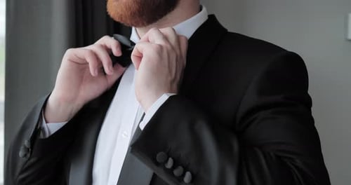 Man Adjusting Bow Tie in Black Tuxedo