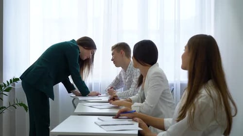 Teacher Helping Students at Desks in Classroom