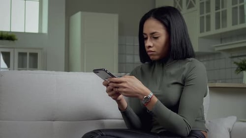 Woman Using Smartphone Relaxing on Sofa Indoors