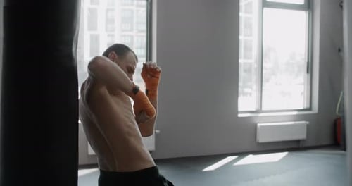Man Boxing Punching Bag in Gym