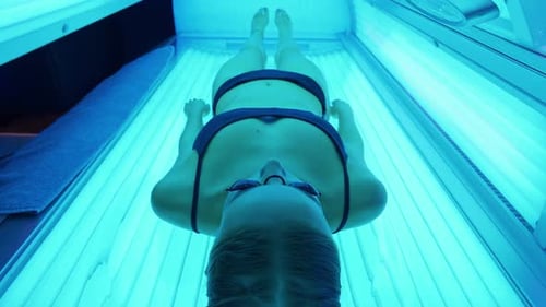 Woman Lying in Tanning Bed with Blue Lights