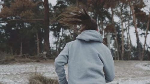 Fit Woman Running Towards Forest in Winter