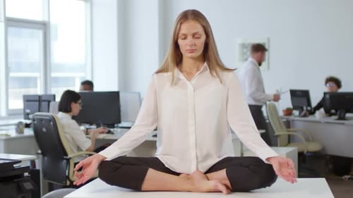 Businesswoman Meditating on Desk in Office