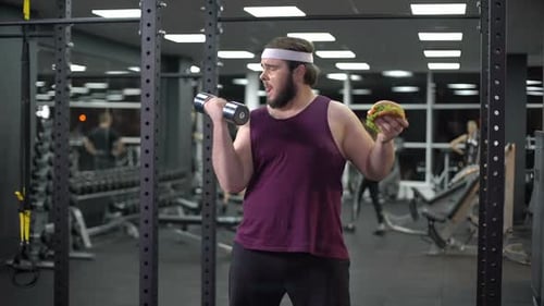 Bearded Man at Gym Holding Burger and Dumbbell
