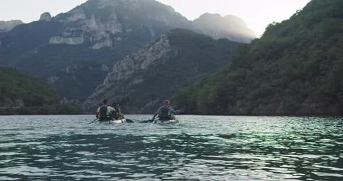 People Kayaking on a Lake Surrounded by Mountains