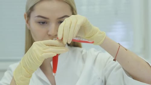 Científico mirando en un tubo de ensayo que rebosa un líquido rojo