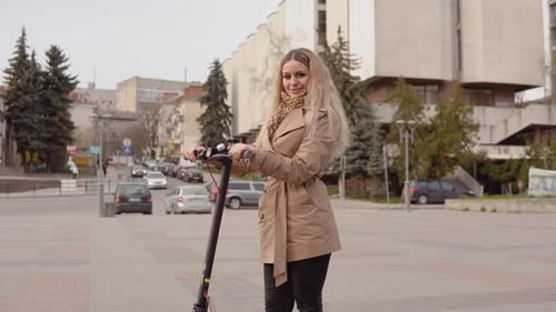 Woman With Electric Scooter Standing in Urban Square
