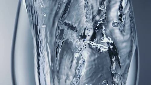 Extreme slo-motion close-up ice dropped into water glass, Slow Motion