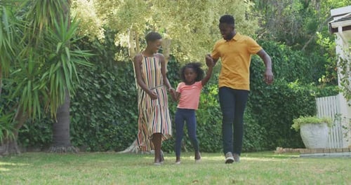 Family Walking in Green Yard Holding Hands, Bright Daytime