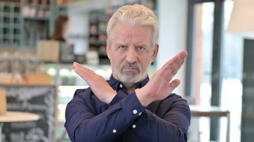 Senior Man Rejects Idea with an X Gesture