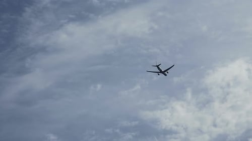 Airplane Flying Through Blue and White Cloudy Sky
