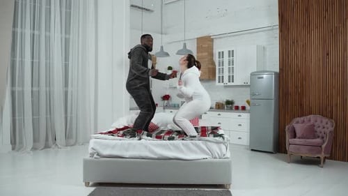 Playful Couple Jumping on Bed at Home