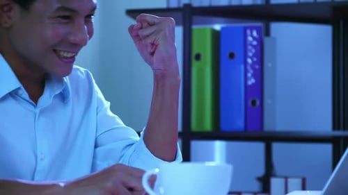 Office man looked at the laptop and he smiled and raised his hand, showing signs of joy