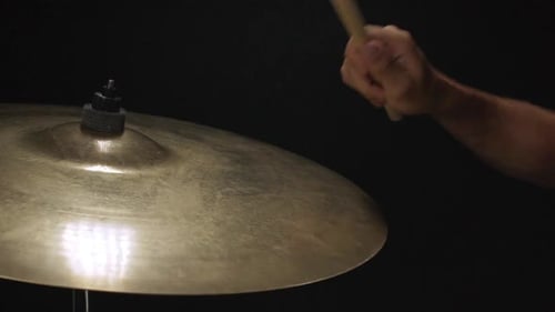 Primer plano de un chico tocando el tambor con una baqueta en cámara lenta