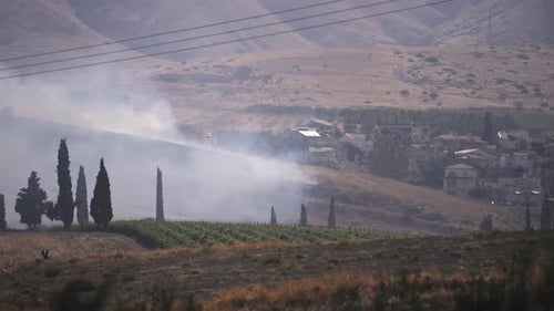 Smoke Rising Over Village in Rural Landscape