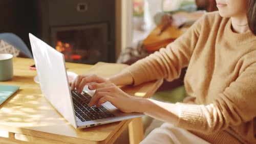 Woman Works on Laptop with Guitar Player in Background