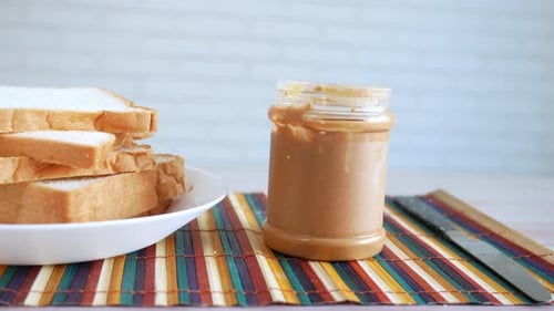 Jar of Peanut Butter Next to Stacked Bread