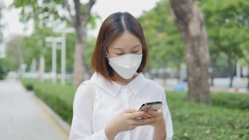 Woman Using Smartphone While Walking Outdoors