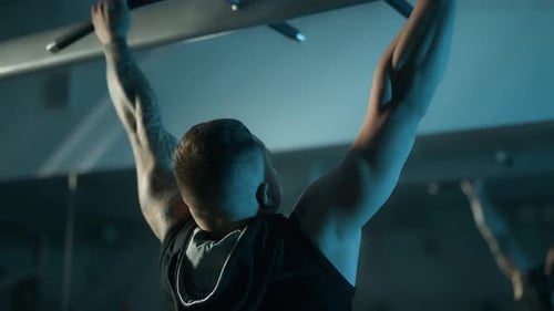 A Handsome Young Muscular Sportsman is Doing Exercise on a Fitness Machine in the Gym