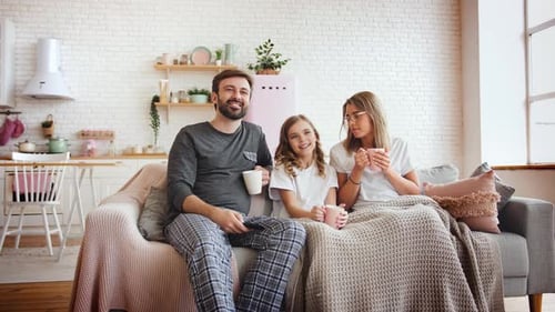 Family Sitting on Sofa Watching TV at Home