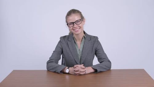 Smiling Woman in Blazer Sits at Desk