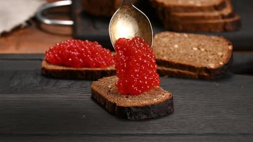Spoon Adding Red Caviar to Bread