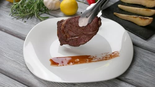 Chef Places Steak on Plate with Sauce