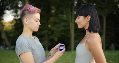 Woman Proposing Marriage to Girlfriend in Park