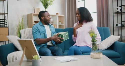 Couple Exchanging Birthday Gifts on Sofa