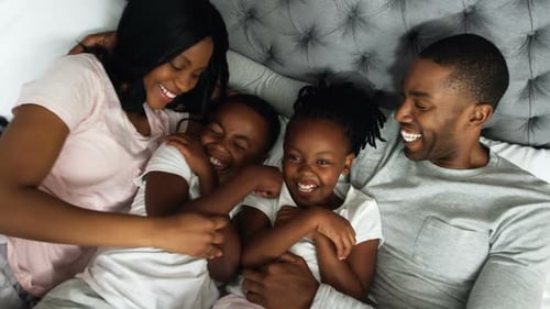 Happy Family Laughing Together in Bed