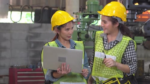 Asian female worker discussing and checking on machine at factory