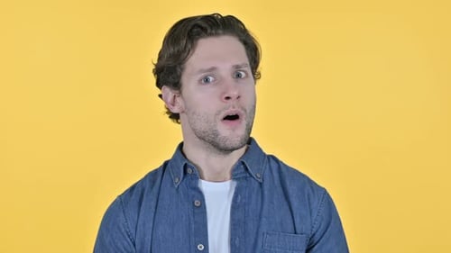 Man Reacts with Shocked Expression on Yellow Background
