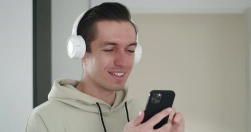 Young Adult Smiling at Phone Wearing Headphones