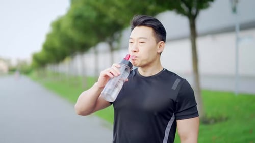 Atleta cansado, agotado y deshidratado, corredor, bebiendo una botella de agua después del entrenamiento