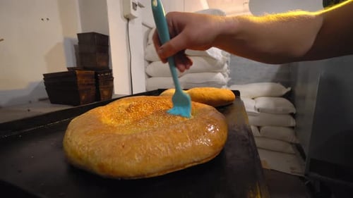 ein Koch kämmt schmelzende Butter mit Pinsel auf gebackenem Brot
