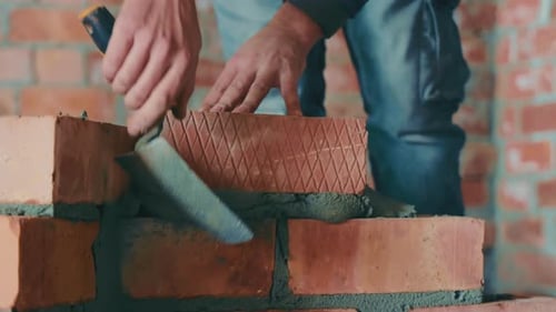 Los maestros colocan ladrillos y construyen el muro de la casa