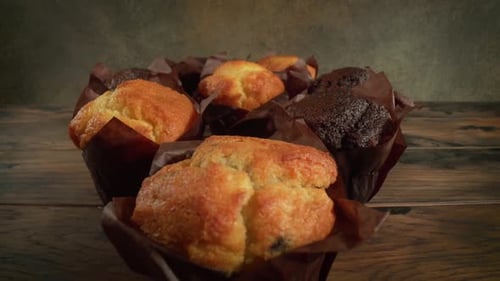 Golden and Chocolate Muffins on Wooden Table