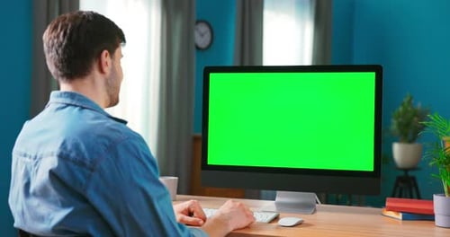 Closeup of a Man Uses Modern Computer with Green Mockup Screen While Sitting at the